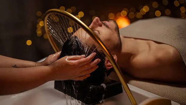 Rinçage et massage du cuir chevelu sous l'arche à eau